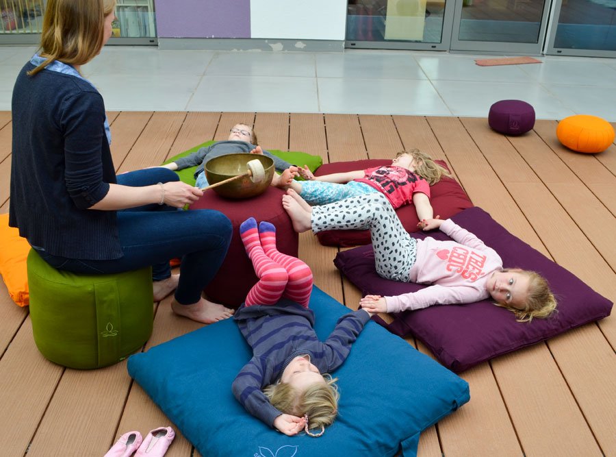 Kinder liegen auf Bodenkissen und nehmen Vibration der Klangschale auf